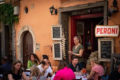 a group of people sitting at tables in a restaurant at Lungaretta Studio Flat [trastevere] in Rome