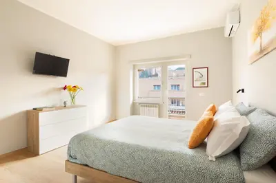 a white bedroom with a bed and a window at Marisa Home in Rome