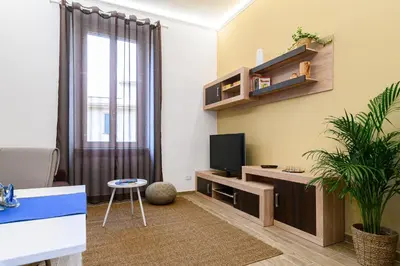 a living room with a tv and a plant at Vatican Bells with Balcony View of St Peters Dome Two Bedrooms Two Bathrooms in Rome