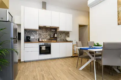 a kitchen with white cabinets and a table with chairs at Vatican Bells with Balcony View of St Peters Dome Two Bedrooms Two Bathrooms in Rome