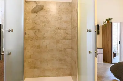 a shower in a room with a stone wall at Vatican Bells with Balcony View of St Peters Dome Two Bedrooms Two Bathrooms in Rome