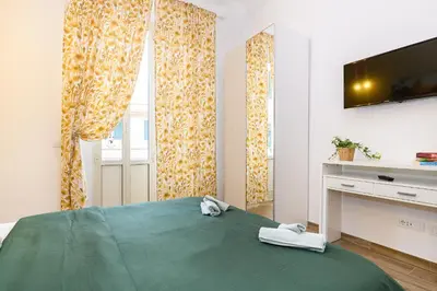 a bedroom with a green bed and a television at Vatican Bells with Balcony View of St Peters Dome Two Bedrooms Two Bathrooms in Rome