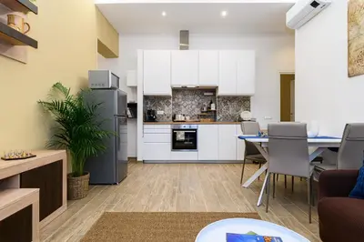 a kitchen and dining room with white cabinets and a table at Vatican Bells with Balcony View of St Peters Dome Two Bedrooms Two Bathrooms in Rome