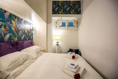 a small white bedroom with towels on a bed at Gianicolo Holiday House in Rome