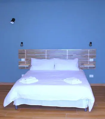 a bedroom with a large white bed with a blue wall at Monolocale Urban House Marconi in Rome