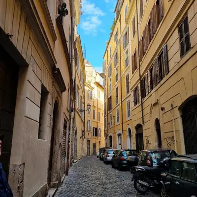 an alley with cars parked on a street between buildings at Casa Nicoletta in Rome