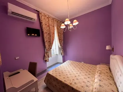 a bedroom with purple walls and a bed and a chair at Guest House Biondi Cavour in Rome