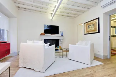 a living room with white chairs and a fireplace at Luxury Charme between Pantheon and Spanish Steps in Rome