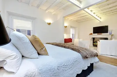 a white bedroom with a large bed and a fireplace at Luxury Charme between Pantheon and Spanish Steps in Rome