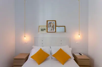 a bedroom with a white bed with two yellow pillows at Hotel Cathrine in Rome