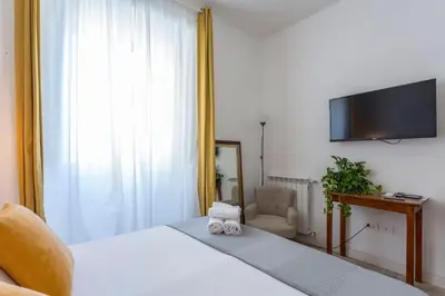 a bedroom with a bed with a television and a chair at Hotel Cathrine in Rome