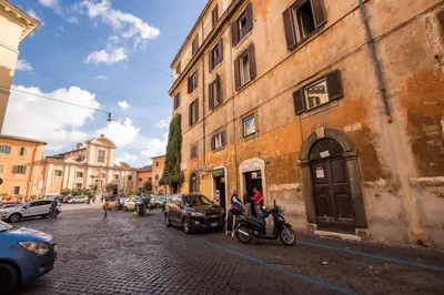 a street with cars and motorcycles parked next to a building at Trastevere Miracle Suite in Rome