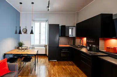 a kitchen with black cabinets and a wooden table at Tolemaide Orange Apartment in Rome