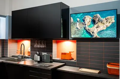a kitchen with a sink and a tv on the wall at Tolemaide Orange Apartment in Rome