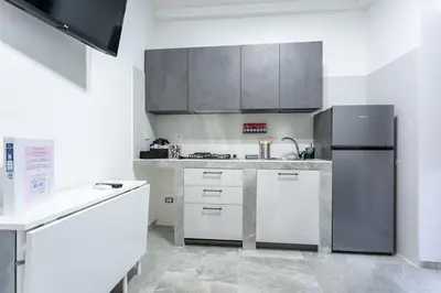 a kitchen with a stainless steel refrigerator and white cabinets at A casa di Elly 2 in Rome