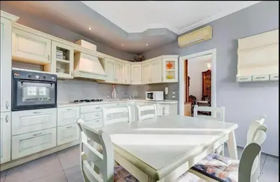 a kitchen with white cabinets and a table with chairs at Domus Testaccio in Rome