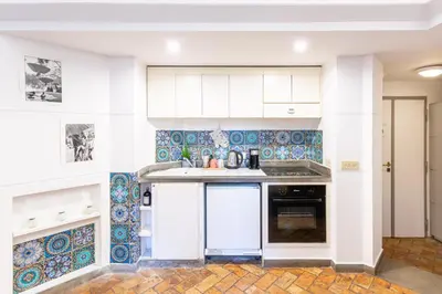 a kitchen with white cabinets and blue tiles at BBB House in Rome