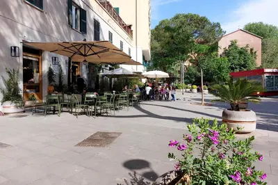 a cafe with tables and chairs and umbrellas on a city street at Roma & Amor Apartment in Rome