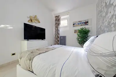a white bedroom with a large bed and a flat screen tv at Roma & Amor Apartment in Rome