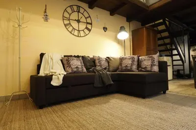 a couch in a living room with a clock on the wall at Loft Germanico in Rome
