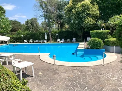 a large blue swimming pool with a table and chairs at Aurelia House Garden in Rome