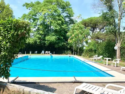 a blue swimming pool with chairs and trees at Aurelia House Garden in Rome