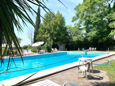 a large swimming pool with chairs and an umbrella at Aurelia House Garden in Rome