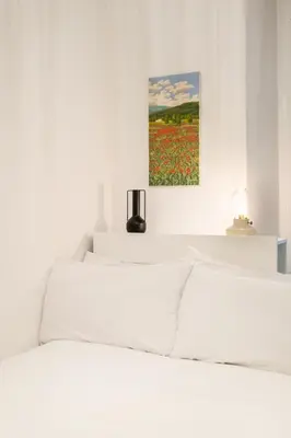 a white bedroom with a bed with a painting on the wall at DOMUS TRAIANA in Rome