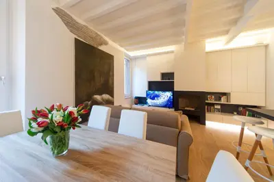 a dining room and living room with a vase of flowers on a table at Banchi Nuovi, modern and cozy apartment in Rome