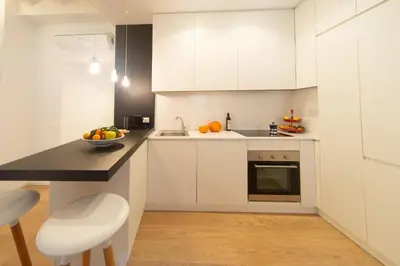 a kitchen with white cabinets and a bowl of fruit on a counter at Banchi Nuovi, modern and cozy apartment in Rome