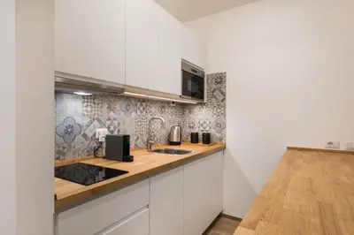 a kitchen with white cabinets and a wooden counter top at Super Comfort Pisino Street in Rome