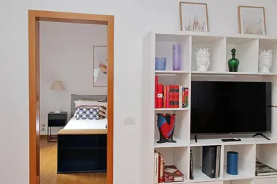 a living room with a television in a white book shelf at Metastasio in Rome
