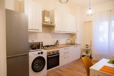 a kitchen with white cabinets and a washer at Angelina's cozy home in Rome