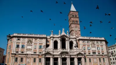 a building with a clock tower and a flock of birds at Rome Near Colosseum in Rome