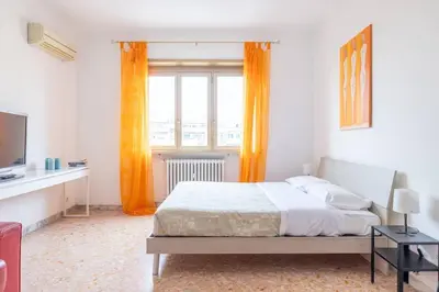 a bedroom with a bed and a window with orange curtains at Ambra's bright apartment in Rome