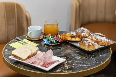 a table with a tray of breakfast foods and a glass of orange juice at TimeRoma Suites in Rome