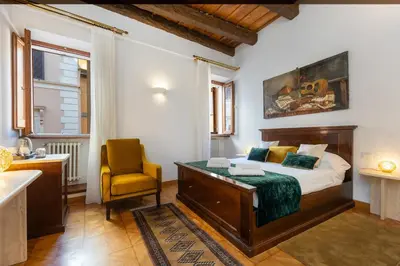 a bedroom with a bed and a chair and a sink at TimeRoma Suites in Rome