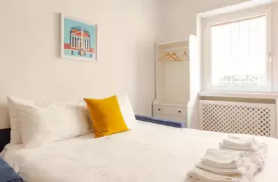 a bedroom with a white bed with a yellow pillow at Comodo appartamento a pochi passi dalla fermata Porta Metronia Metro C in Rome