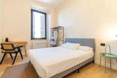 a bedroom with a bed and a desk and a chair at Cunabu Apartments in Rome