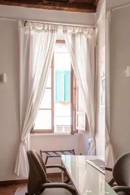 a window with white curtains and a glass table and chairs at BQA San Crisogono Apartments Rome-Trastevere in Rome