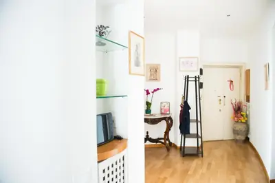 a living room with white walls and a tv and a hallway at BaccaLia Home in Rome