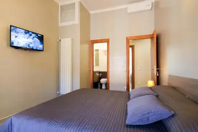 a bedroom with a bed and a television on the wall at San Pietro's Home - Guesthouse in Rome
