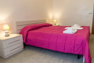 a bedroom with a pink bed with towels on it at San Pietro's Home - Guesthouse in Rome