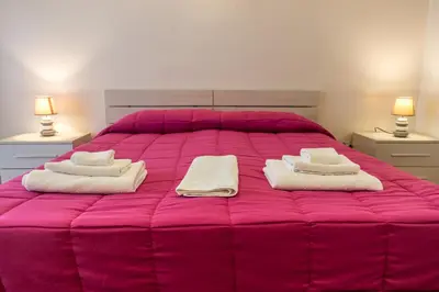 a pink bed with two towels and two lamps at San Pietro's Home - Guesthouse in Rome