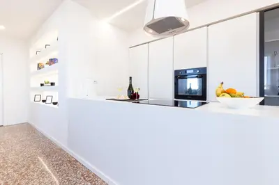 a kitchen with white cabinets and a counter with a bowl of fruit at Adventura Penthouse in Rome