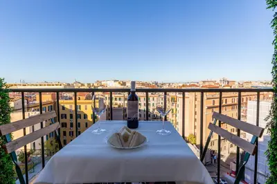 a table with a bottle of wine and glasses on a balcony at Adventura Penthouse in Rome