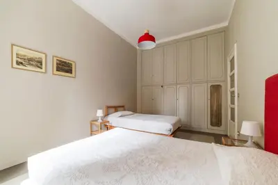 a white bedroom with two beds and a red lamp at GuestHost - Piazza Bainsizza Elegant Apartment in Rome