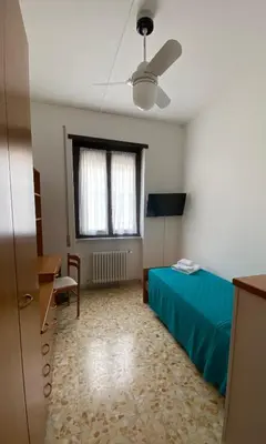 a room with a bed and a desk and a window at Casa Per Ferie Casa Cabrini in Rome
