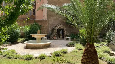 a courtyard with a fountain and a palm tree at Casa Per Ferie Casa Cabrini in Rome