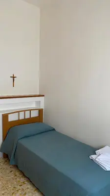 a bedroom with a bed with a cross on the wall at Casa Per Ferie Casa Cabrini in Rome